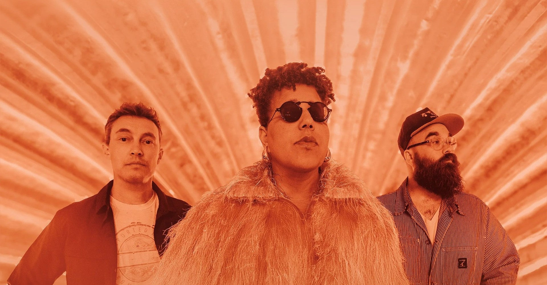 Three people standing together with a red-orange radial gradient background