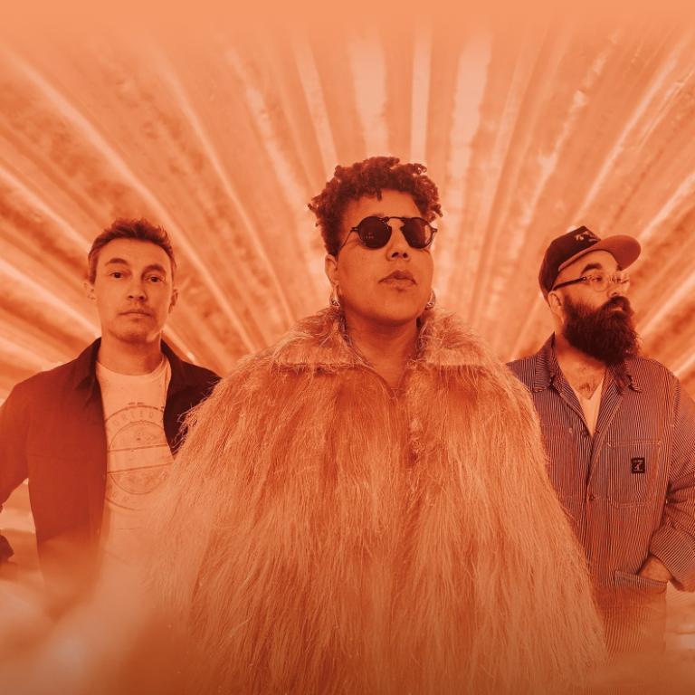 Three individuals standing together with a warm, orange-toned background